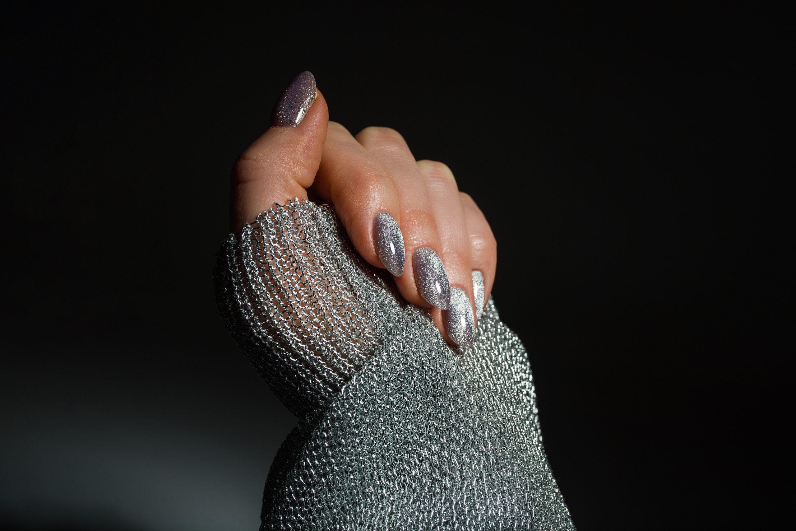 Almond-shaped chrome nails with a silver chrome manicure finish, paired with a metallic silver mesh sleeve.