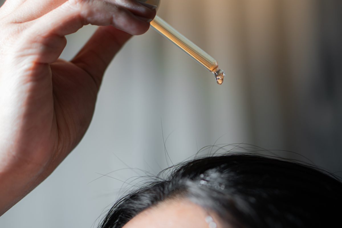 Woman using hair serum to her hair. Hair product.