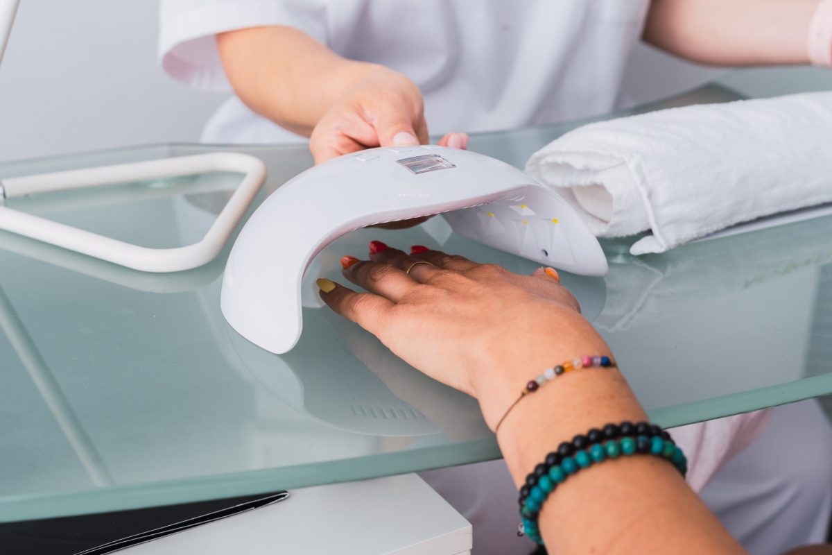 Close-up view of the process of drying nails with gel polish in an ultraviolet lamp at the beauty spa.