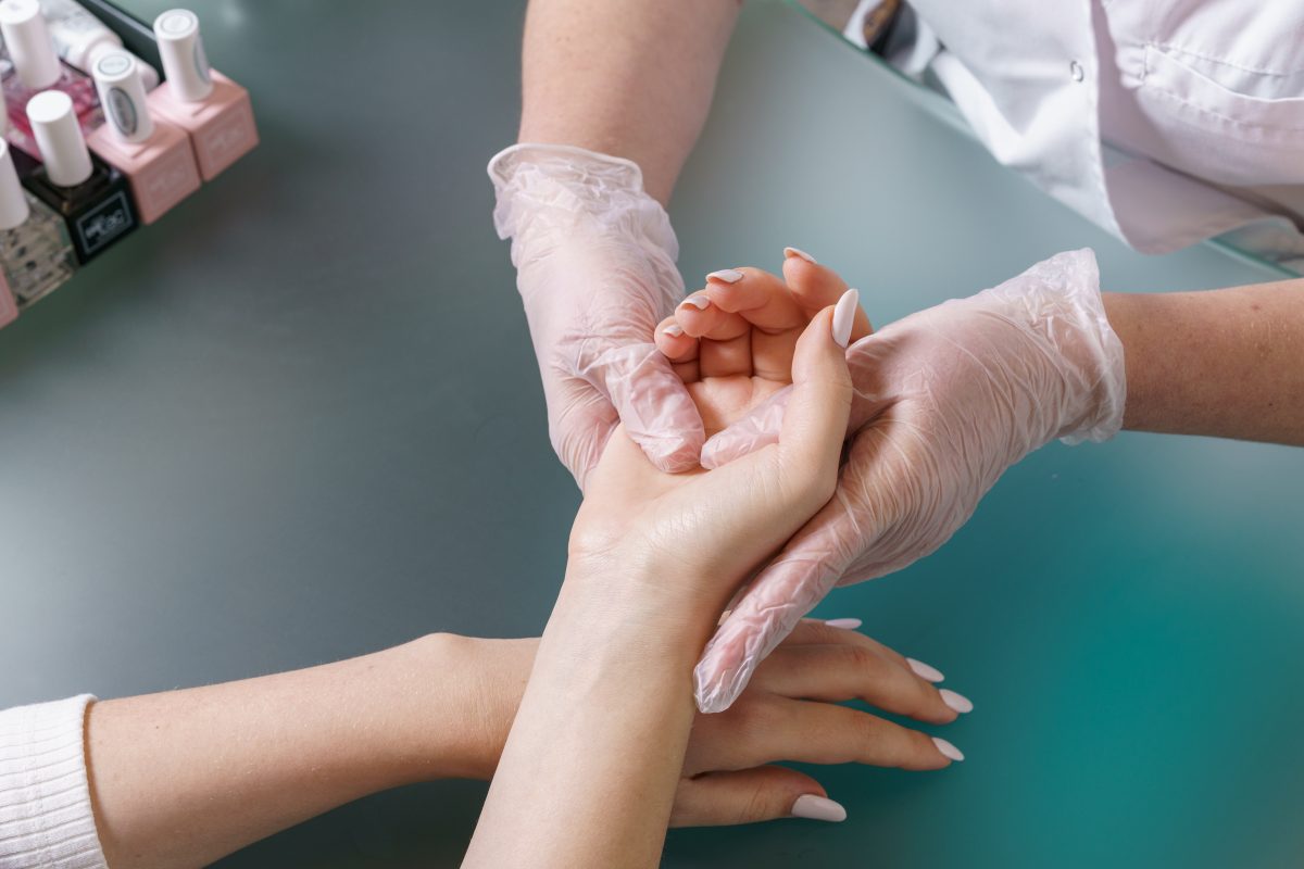 Manicurist does professional light hand massage after manicure procedure. Monthly self-care. An additional bonus to the procedure in the beauty salon. Relaxation of hands after a hard day. Close-up