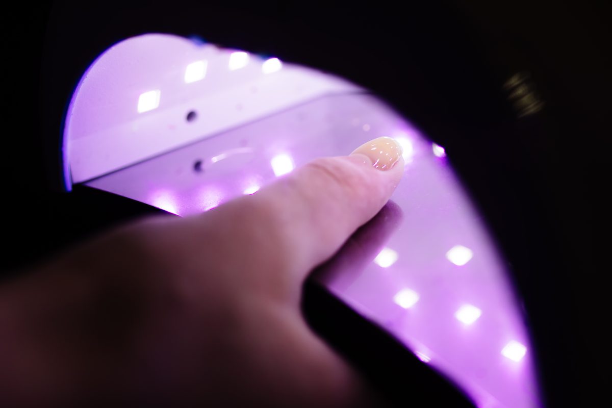 UV lamp gel polish manicure process in a beauty salon. Salon procedure. The master coats the client's nails with a varnish. Professional Nail Lamp