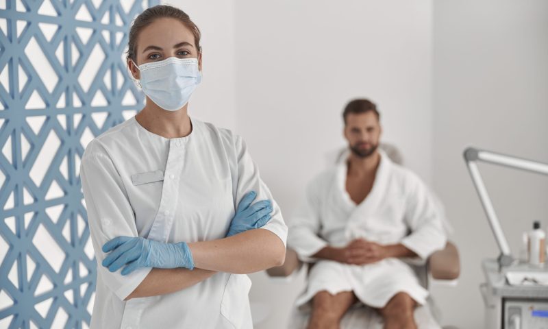 Beauty professional wearing a protective mask and gloves.