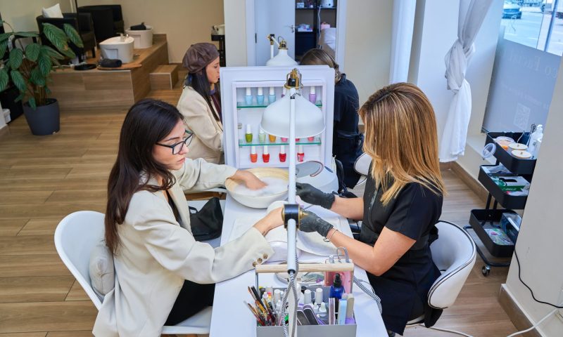 Clients at manicure stations in a salon.